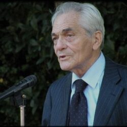 Professor Jacques-Louis Binet at a speaking engagement in front of a leafy background